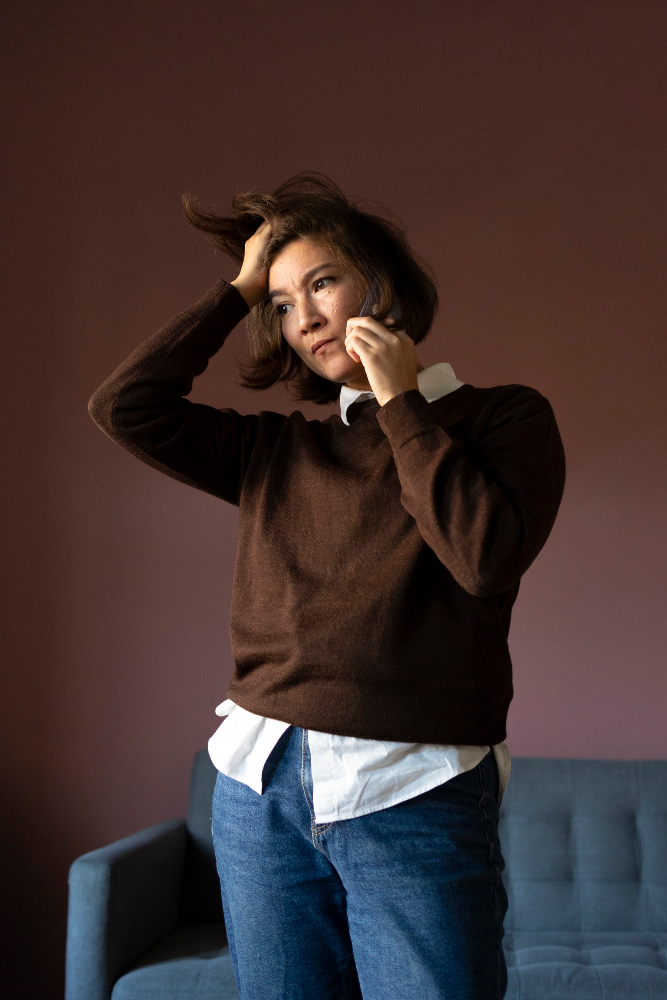 Woman standing with hand in her hair looking distressed, representing emotional struggles addressed through telehealth psychiatry