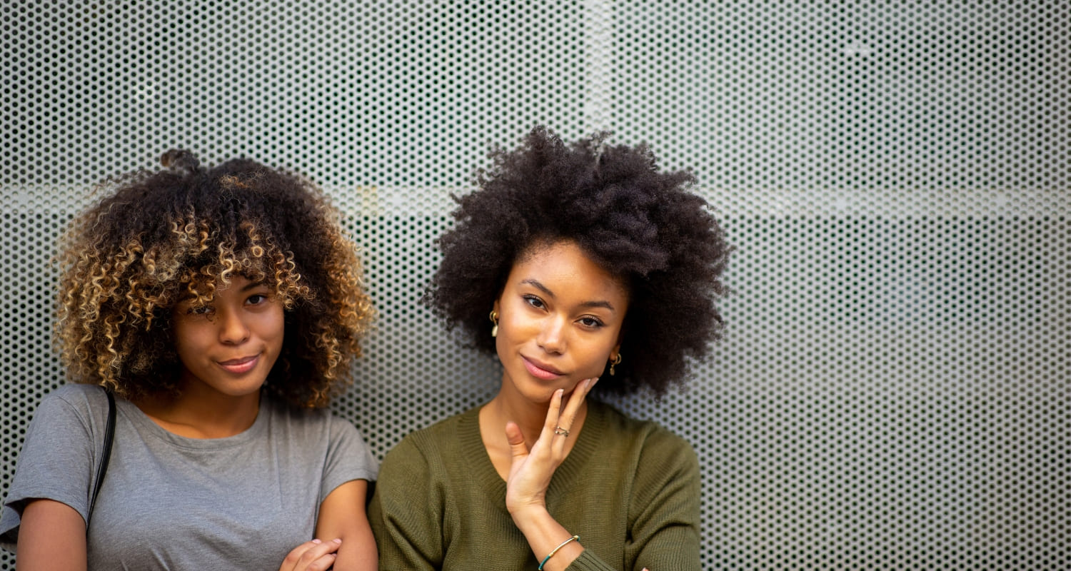 Two confident women standing together, representing improved self-esteem and confidence through mental health support