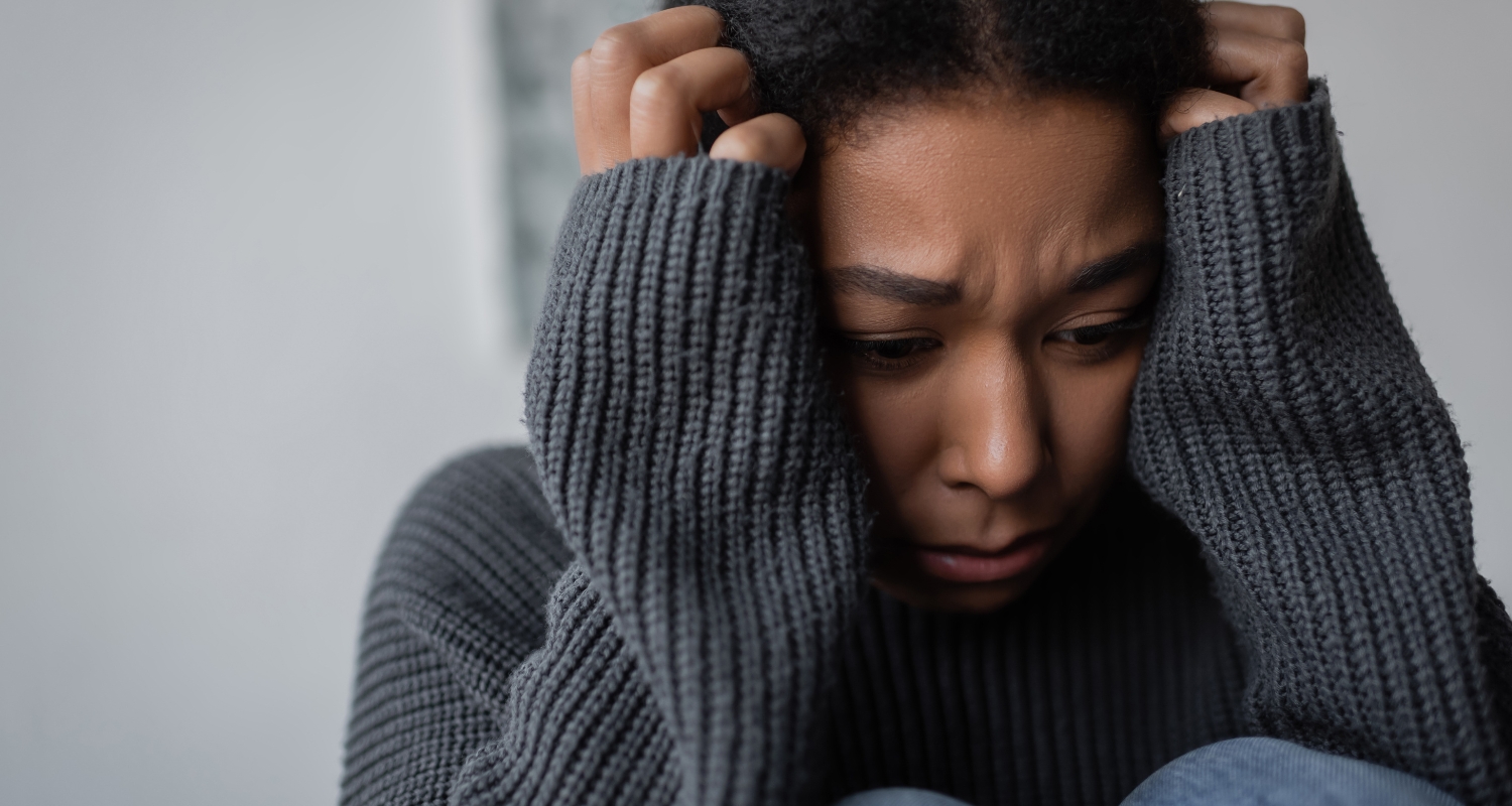 Woman gripping her head with an expression of intense distress, representing panic attack symptoms