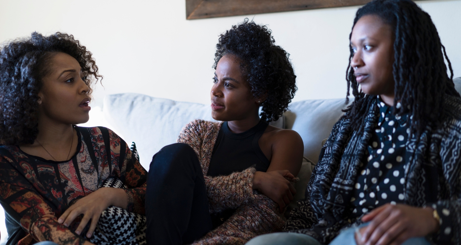 Three women sitting together in conversation, representing community support for women's mental health concerns