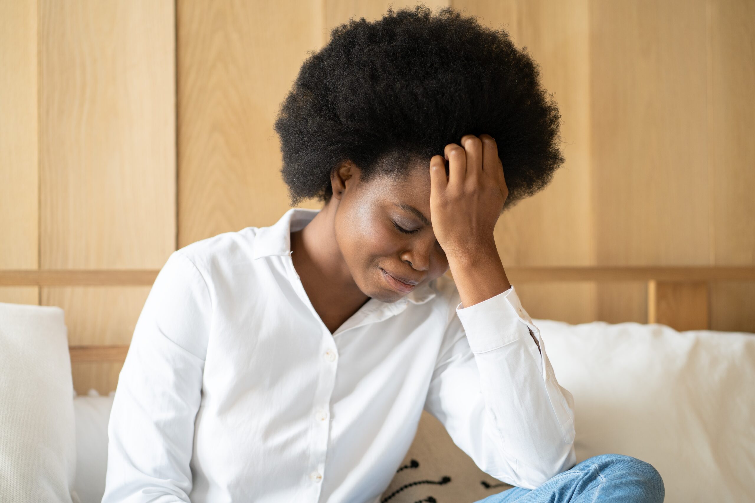 Woman sitting with hand on head looking stressed and overwhelmed, representing stress and burnout