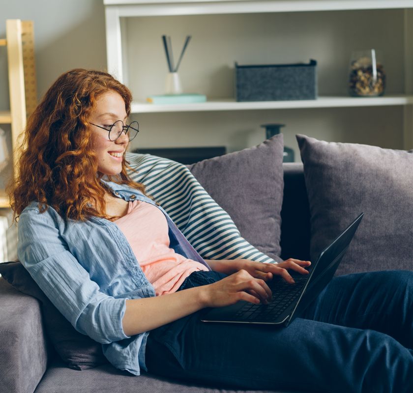 Woman relaxing on her couch at home during a telehealth psychiatric evaluation on her laptop