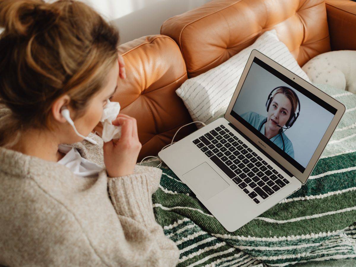 Woman at home on a telehealth video visit with a provider on her laptop