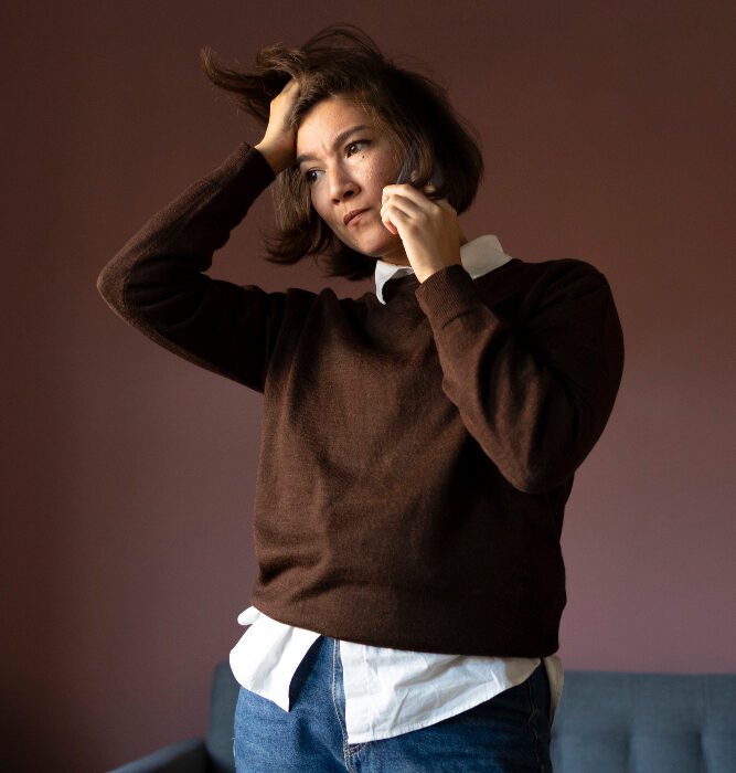 Woman standing with hand in her hair looking distressed, representing emotional struggles addressed through telehealth psychiatry