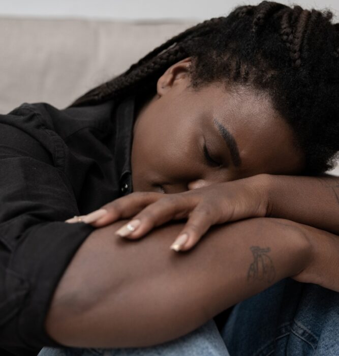 Woman slumped with head resting on her arms looking exhausted, representing mood disorder symptoms
