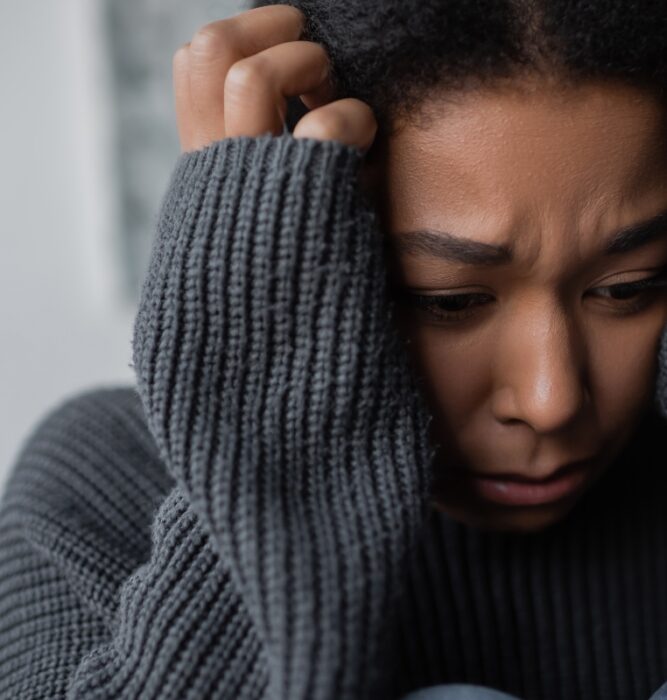 Woman gripping her head with an expression of intense distress, representing panic attack symptoms