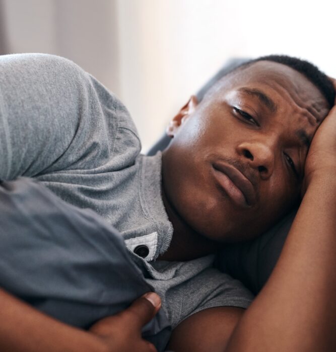 Man lying in bed awake with hand on head, representing insomnia and sleep problems